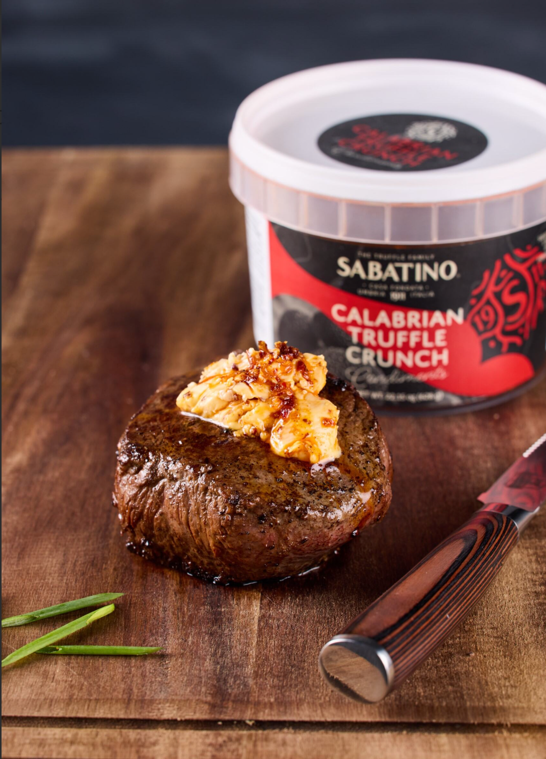a piece of meat with a knife and a container of food