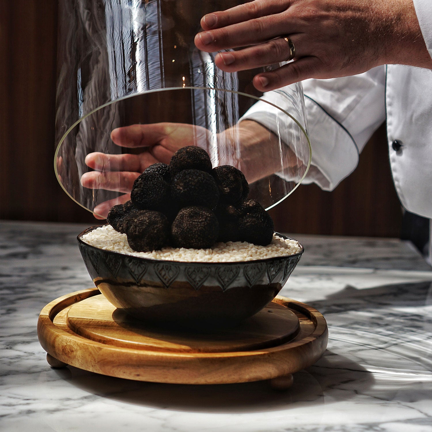 Bowl of truffles on a wooden board with a chef's hands in the background