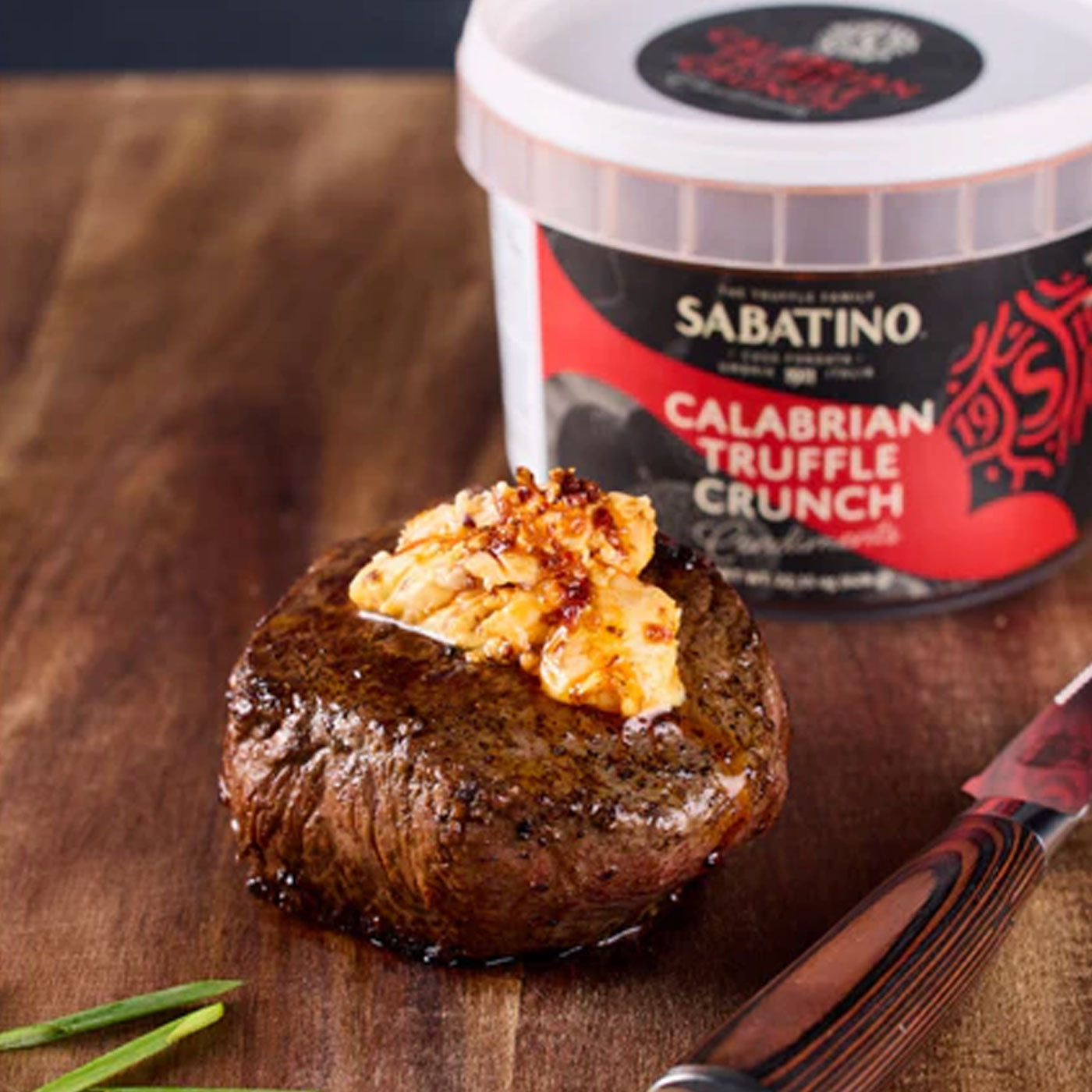 a piece of meat with butter on top next to a knife