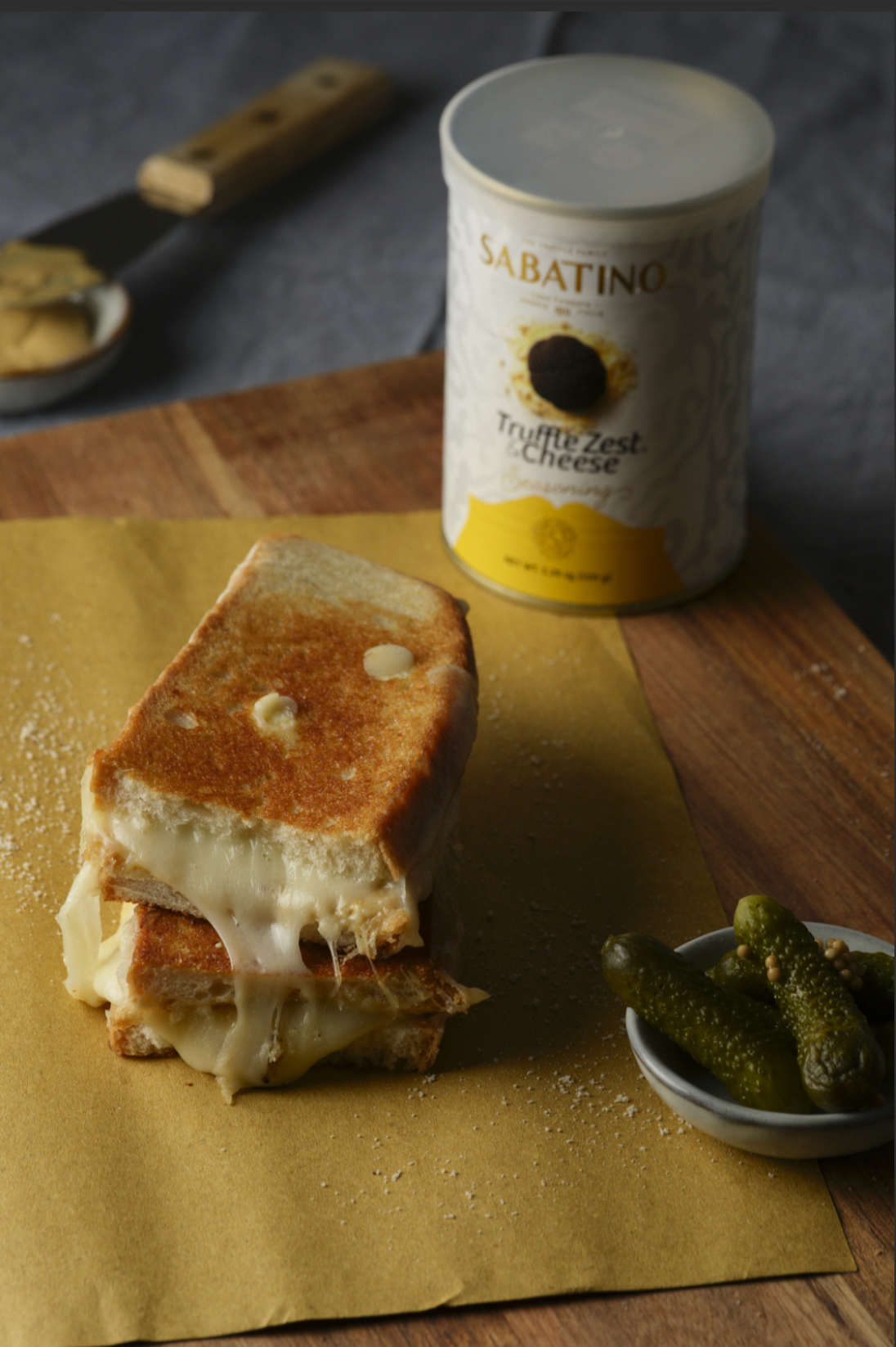a sandwich with cheese and pickles on a wooden surface