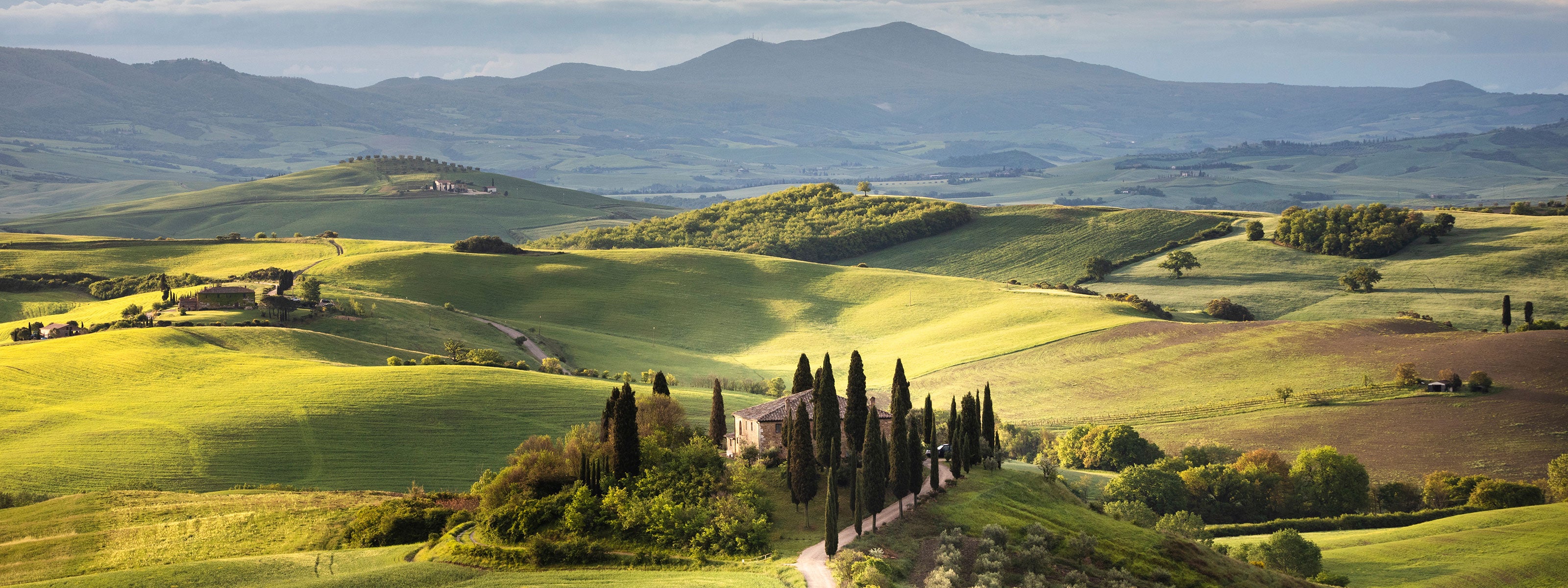 a house on a hill with trees and hills in the background